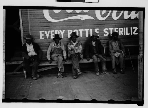 [Men Seated in Front of Coca Cola Sign on Building Facade, New Orleans, Louisiana]