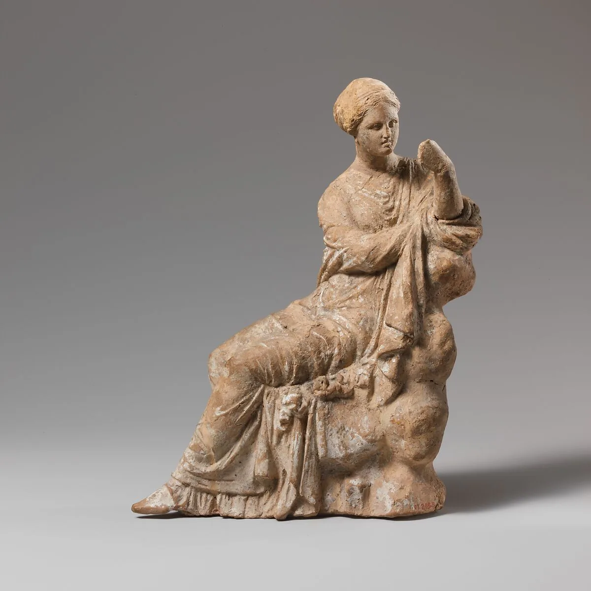 Terracotta statuette of a woman seated on a rock — Unknown
