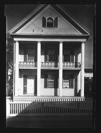 [Greek Revival House with Picket Fence and Iron Lyre Grillwork in Balcony]
