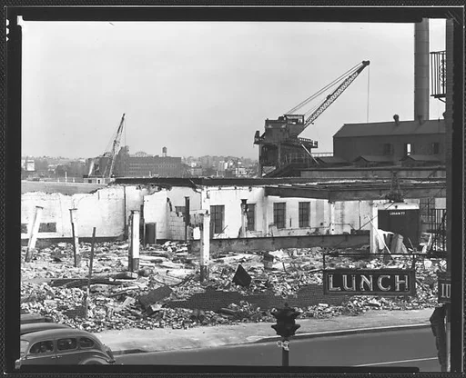 [Demolition Site with Cranes, Cars on Street, and "Lunch" Sign in Foreground New York City]