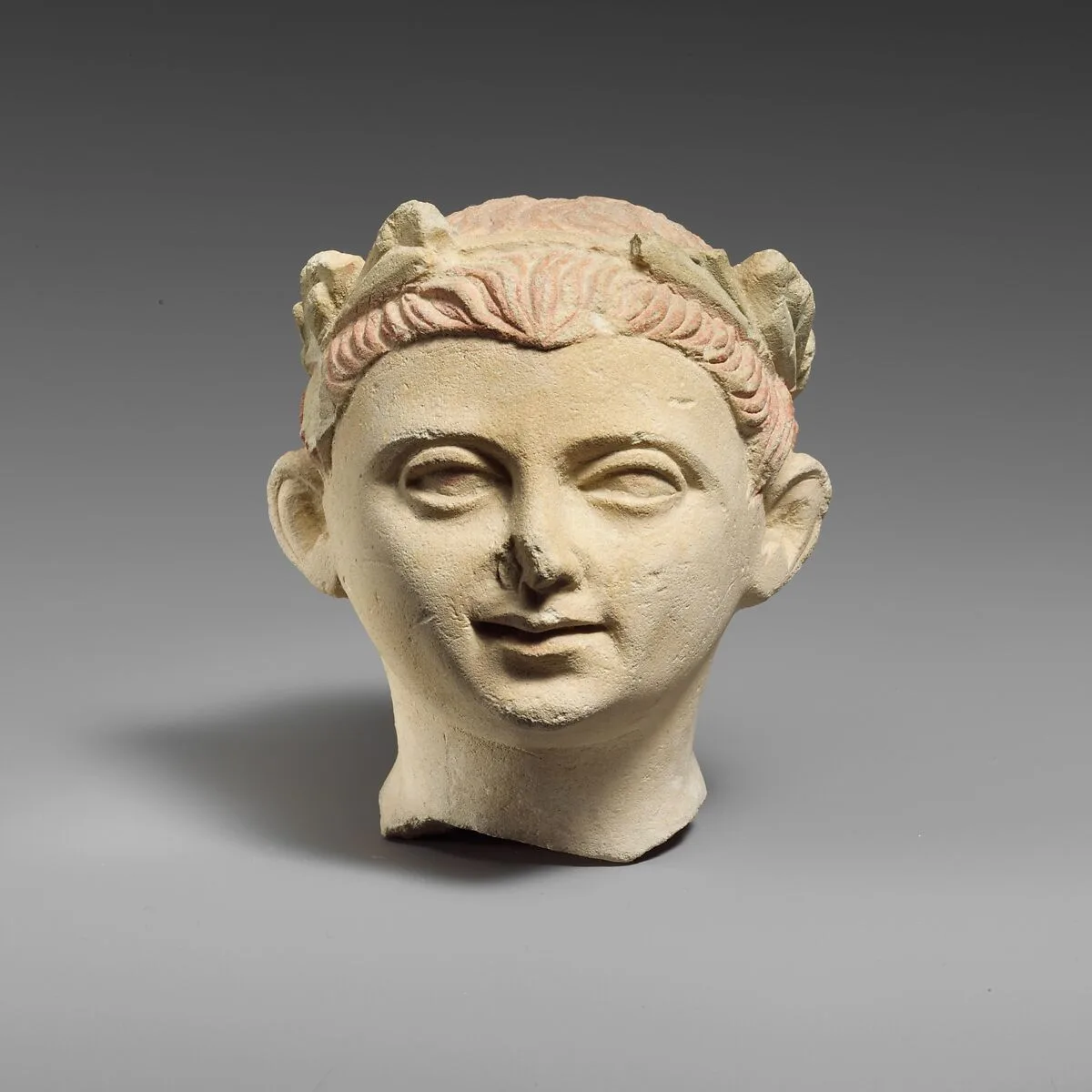 Limestone head of a boy with a wreath of leaves — Unknown