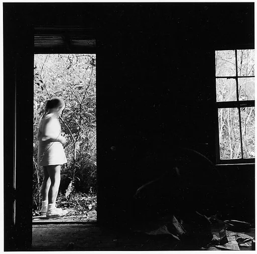 [View Through Doorway of Standing Girl with Crouching Man Inside]