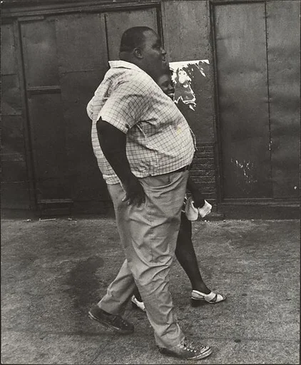 [Man Wearing Short-Sleeved Plaid Shirt and Woman in Sandals Walking on Street, New York]