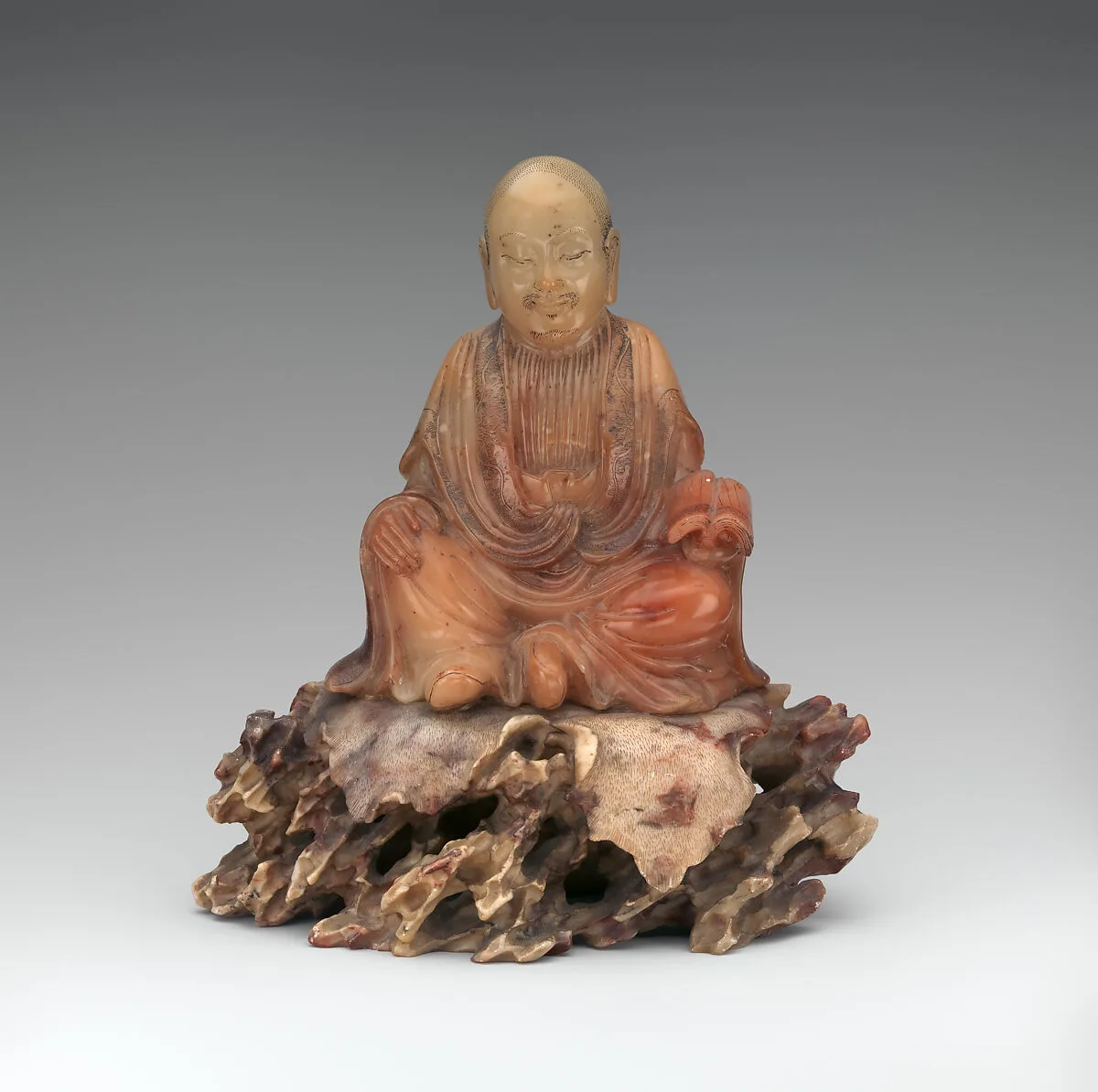 清 壽山石雕靜坐羅漢|Seated luohan holding a book — Unknown