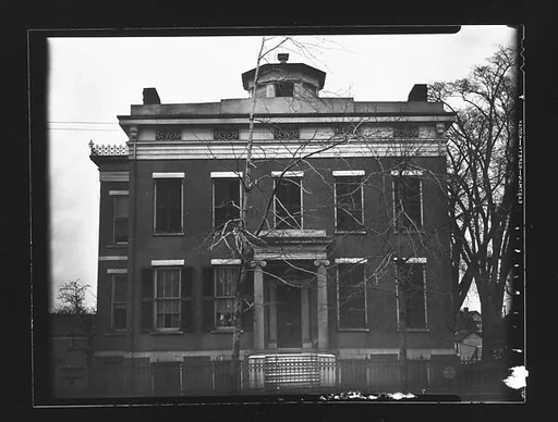 [Greek Revival House with Octagonal Belltower Behind Iron Fence]