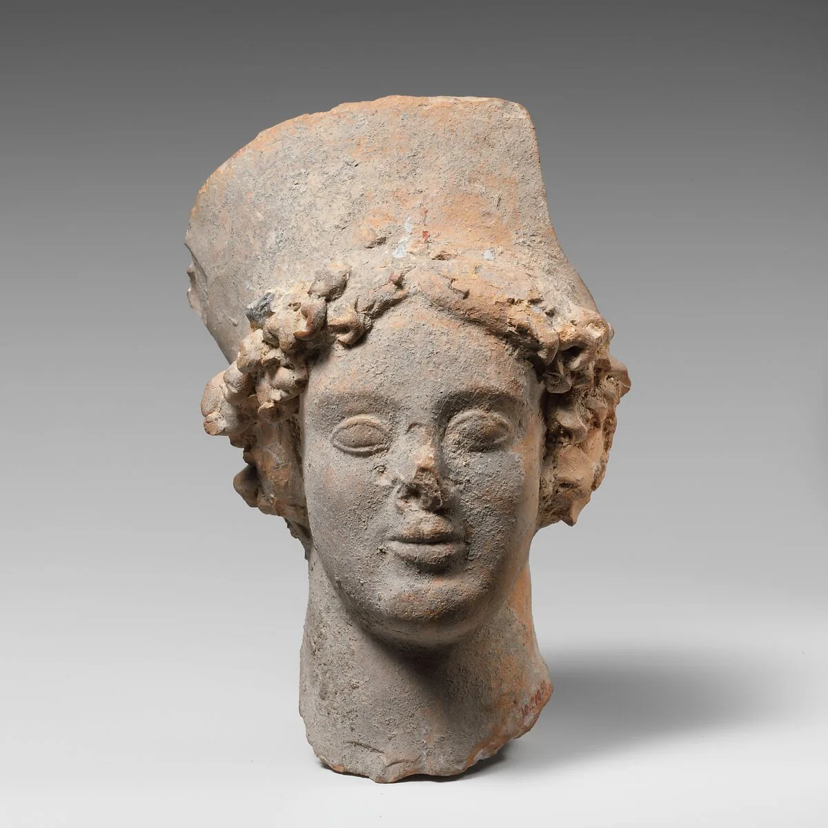 Terracotta head of a woman wearing a high headdress — Unknown