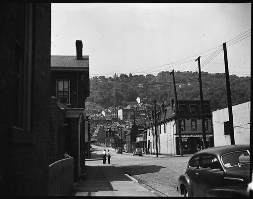 [Street Scene with Houses on Hillside in Distance]