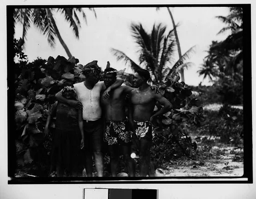 [South Seas: Cressida Sailor Posing for Portrait with Two Men in Sarongs and a Woman on Shore]