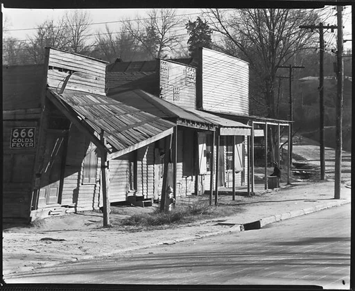 [Oblique View of Roadside Stores with Ads for 666 Cold Remedy, Vicksburg, Mississippi]