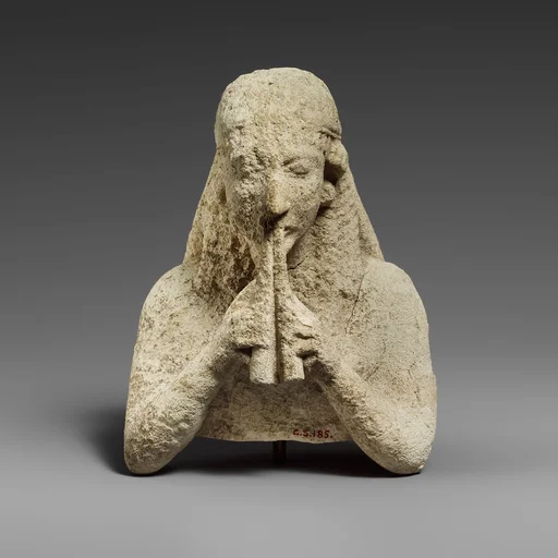 Upper part of a limestone statuette of a female aulos player