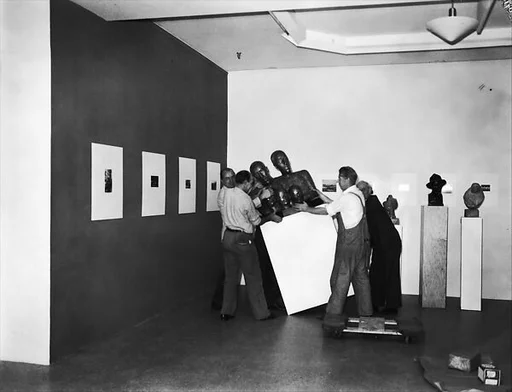 [Installation View of "Walker Evans: American Photographs"  Exhibition with Workmen Moving Sculpture, The Museum of Modern Art, New York City]