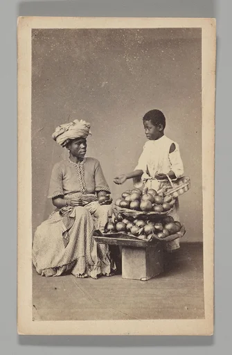 [Studio Portrait: Seated Woman and Standing Boy Street Vendors with Vegetable Baskets, Brazil]