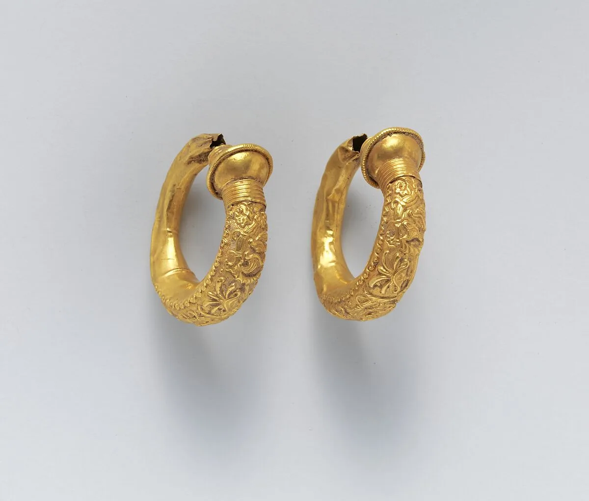 Gold trumpet-shaped earrings with relief decoration — Unknown