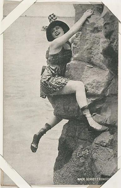 Bathing beauty in costume posed climbing rock from Mack Sennett Comedies Arcade series (W423) — Unknown