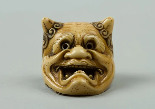 鬼面下の阿亀牙彫根付　銘:民谷|Netsuke of Okame under a Demon Mask