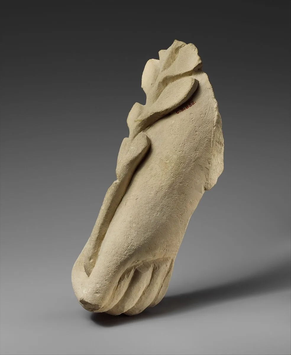 Limestone hand holding a branch of leaves — Unknown