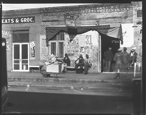 [Groups of Men Seated on Bench and Standing Around Shop Doorway, Selma, Alabama]