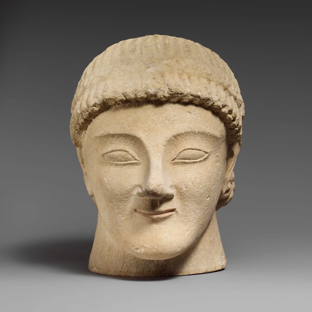Limestone head of a beardless male votary with a wreath of rosettes — Unknown