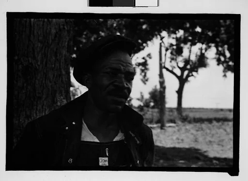 [Man Wearing Cap and Overalls Next to Tree, Hale County?, Alabama]