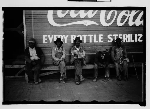 [Men Seated in Front of Coca-Cola Sign on Building Façade, New Orleans Vicinity, Louisiana]