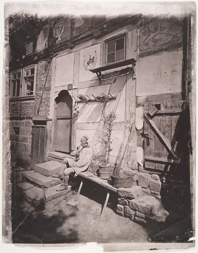 [Man Smoking Pipe Outside His Home on Village Street]