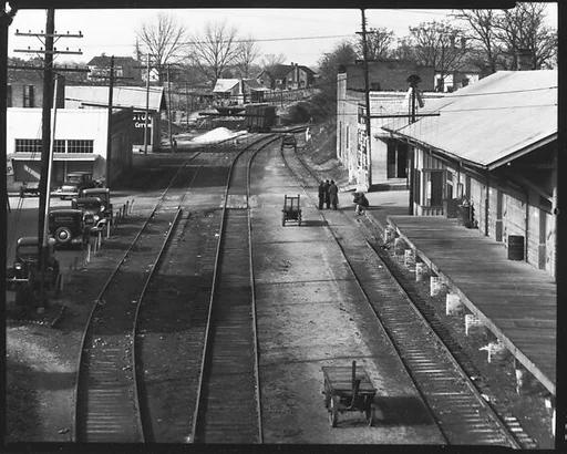[Railroad Tracks Through Town with Parked Cars and Depot on Either Side, Edwards, Mississippi]