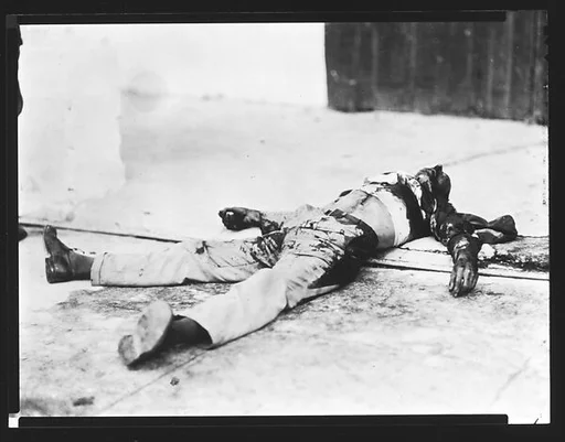 [Copy of Newspaper File Photograph: Blood-Stained Corpse on Street, Havana]