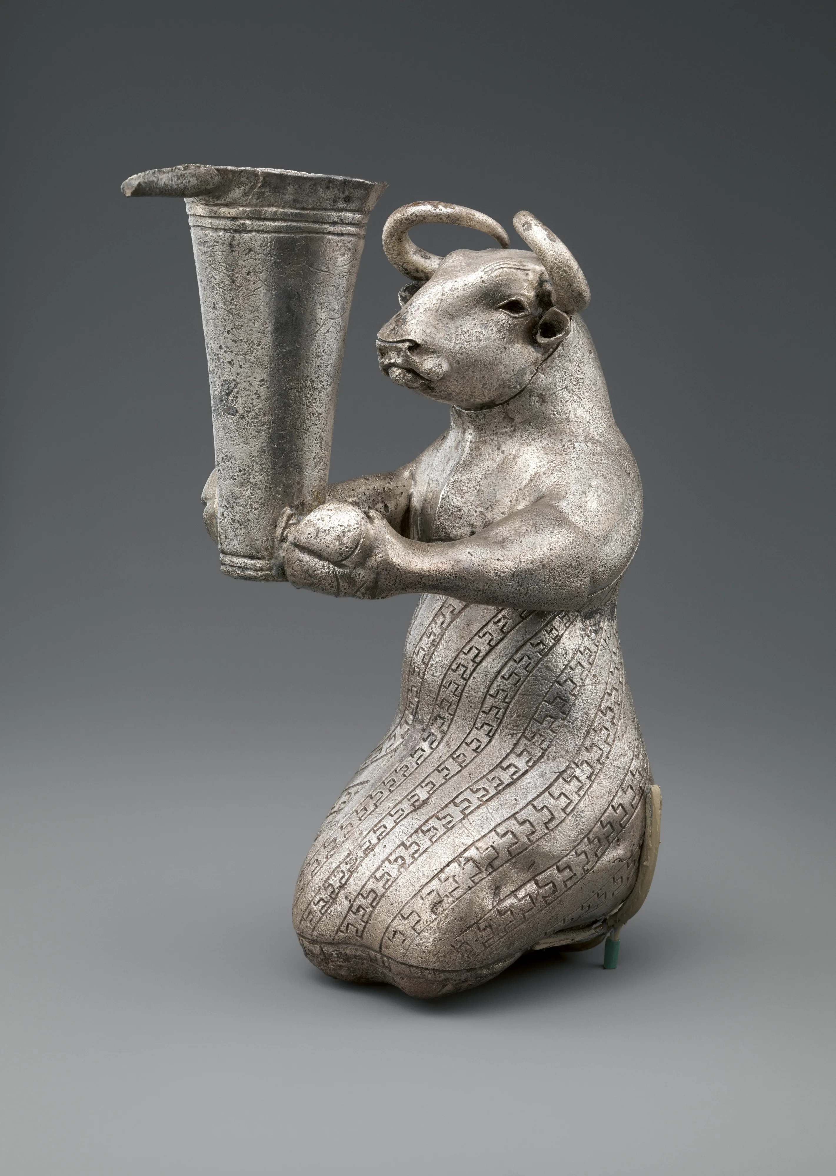 Kneeling bull holding a spouted vessel — Unknown