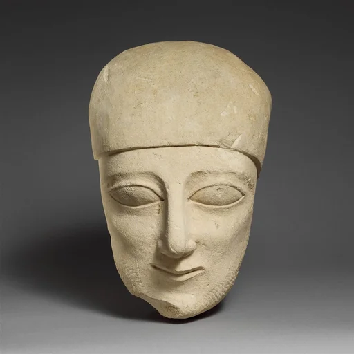 Fragment of a limestone head of a bearded male with a plain headdress