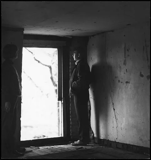 [Guy Davenport and Unidentified Woman in Darkened Room, Looking Through Doorway]