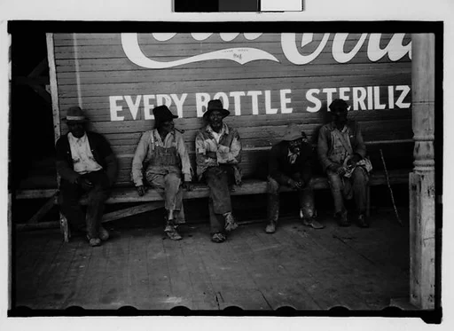 [Men Seated in Front of Coca Cola Sign on Building Facade, New Orleans Vicinity, Louisiana]