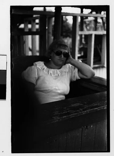 [Two 35mm Film Frames: Sleeping Woman Ticket Taker in Booth at Amusement Park]