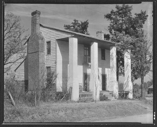 [House with Squared Columns and Rocking Chair on Porch]