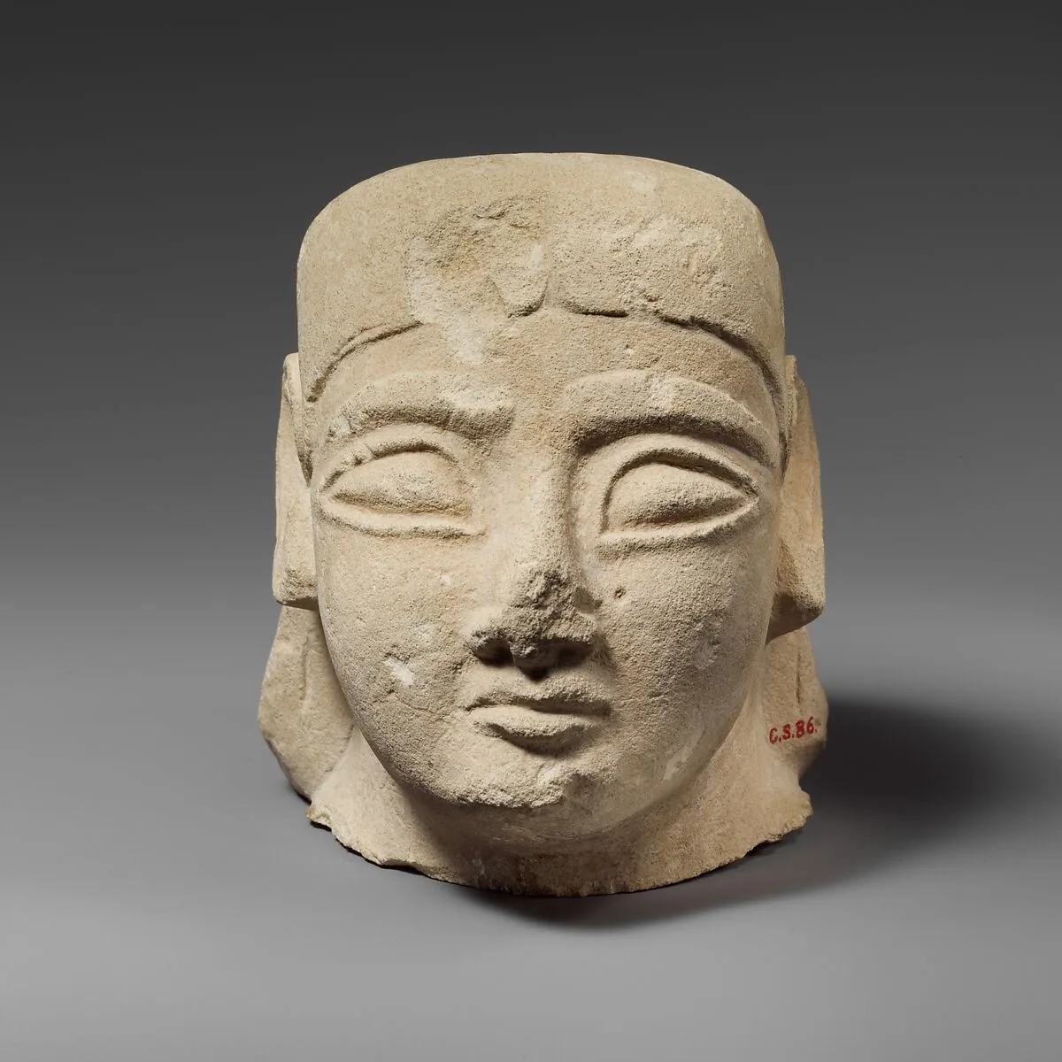 Limestone head of a beardless male with a plain headdress — Unknown