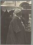 [Man in Traditional Moroccan Costume at Street Fruit Stand, Tangiers, Morocco]