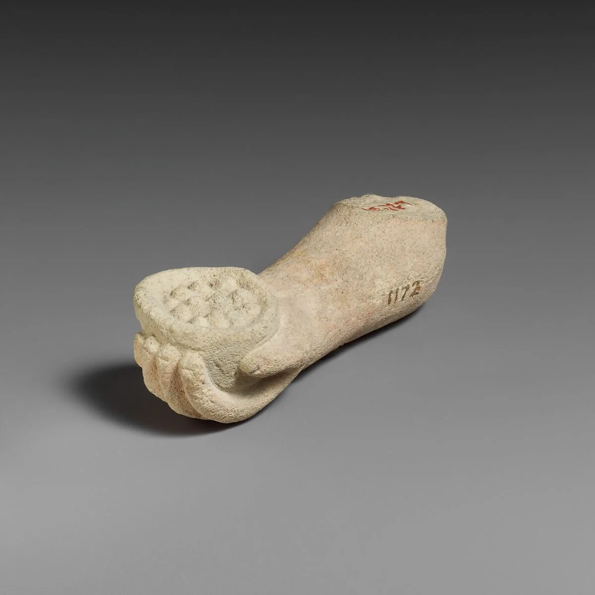 Limestone arm with pieces of fruit (?) held in the hand — Unknown