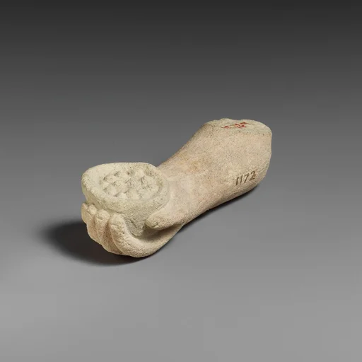Limestone arm with pieces of fruit (?) held in the hand