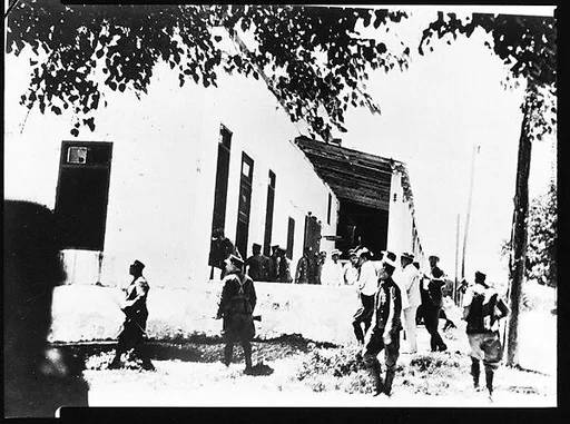 [Copy of Newspaper File Photograph: Crowd Scene with Armed Men in Foreground, Outside Building, Probably Havana]