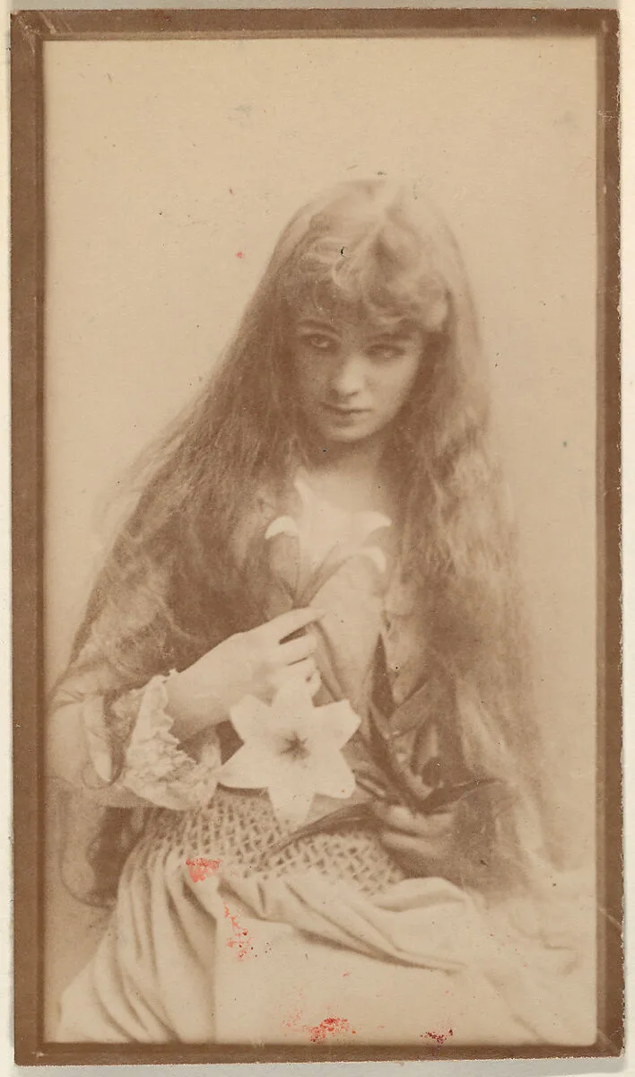 Actress with long hair seated with flower on lap, from the Actresses series (N668) — Unknown