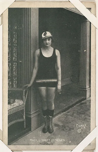 Bathing beauty in costume in interior with hand on wicker chair from Mack Sennett Comedies Arcade series (W423) — Unknown