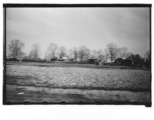 [Wooden Houses Behind Fence in Field, From Moving Automobile, Louisiana]
