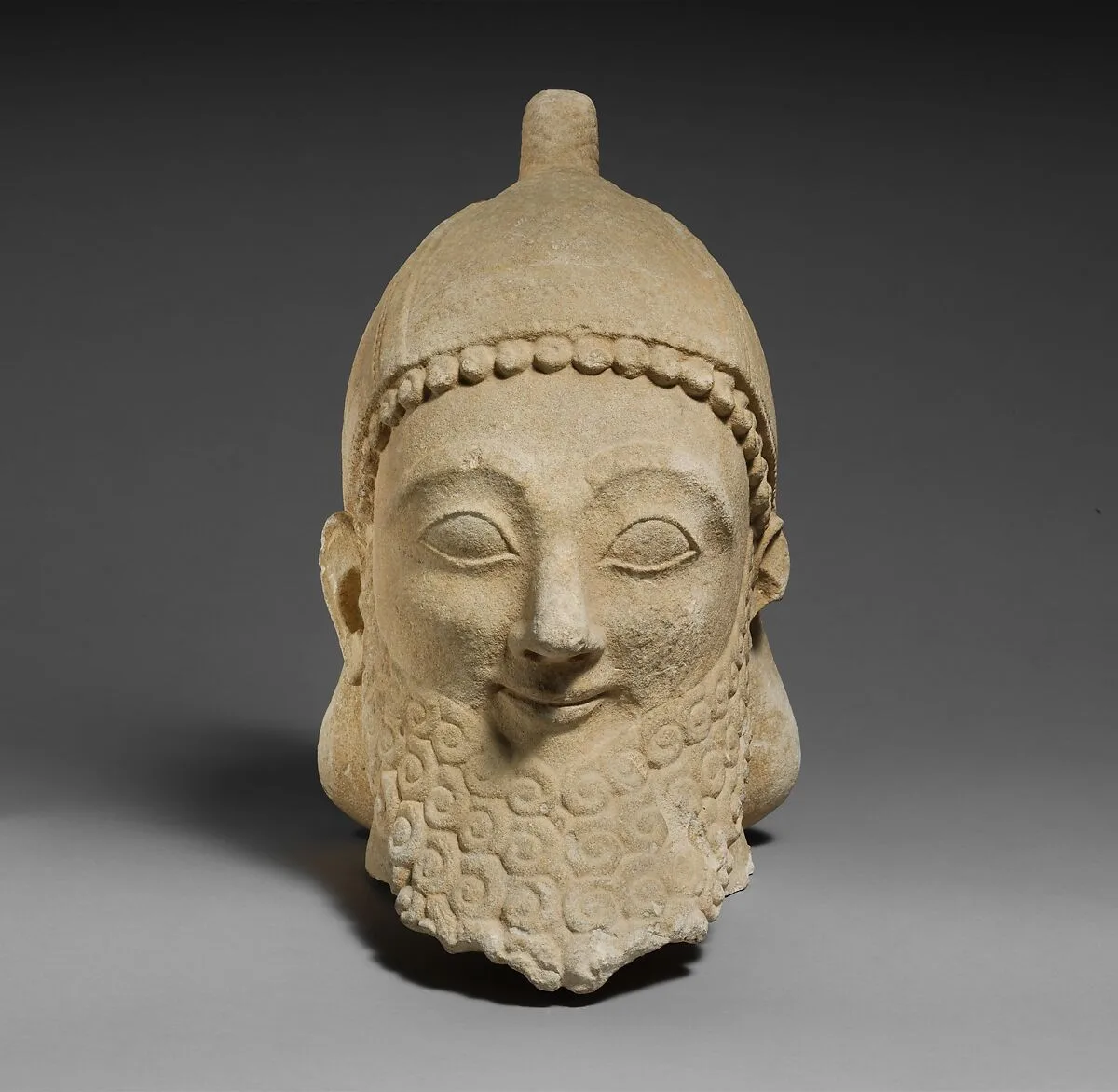 Limestone head of a bearded male wearing a conical helmet — Unknown