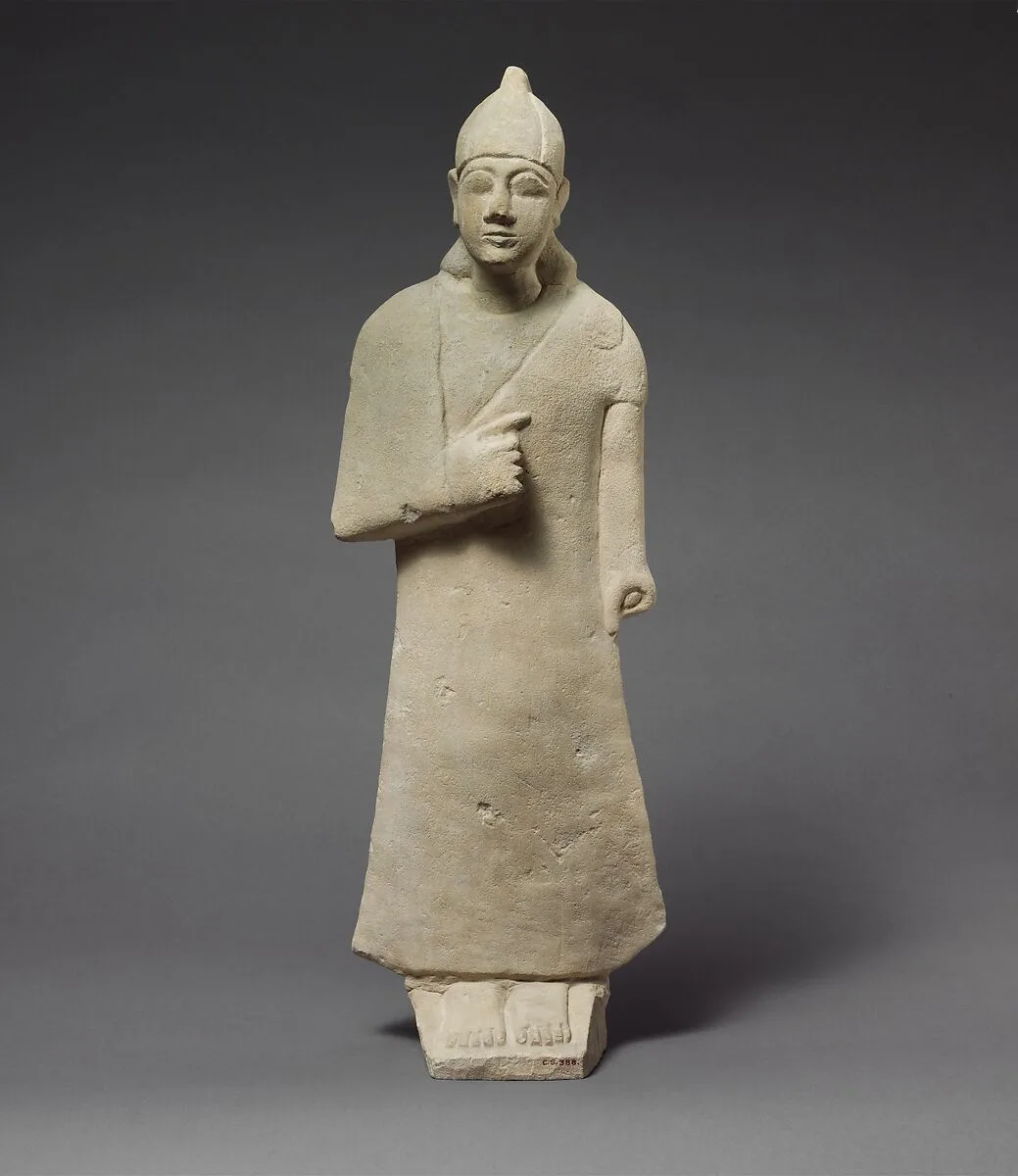 Statuette of a beardless male votary wearing a long garment and a conical helmet — Unknown