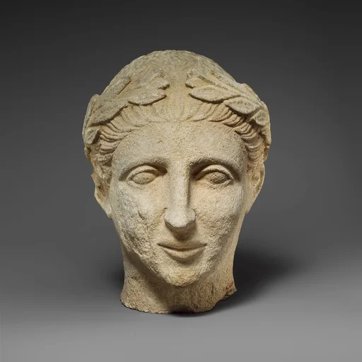 Limestone head of a beardless male votary with a wreath of leaves