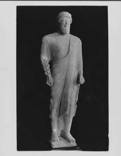 Limestone votary of a bearded male in Greek dress with a wreath