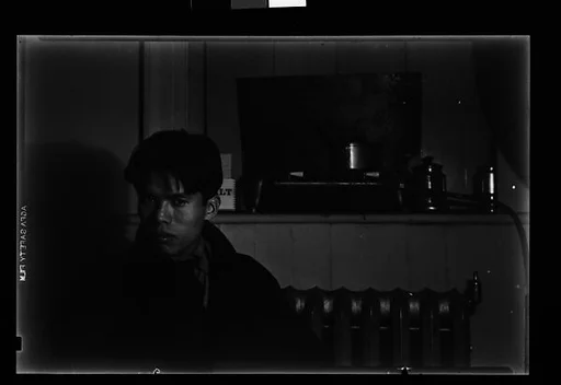[Young Man in Overcoat Seated in Front of Radiator]