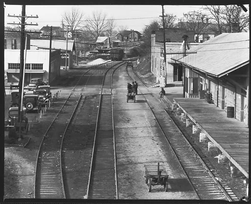 [Railroad Tracks Through Town with Parked Cars, Depot, and Pedestrians, Edwards, Mississippi]