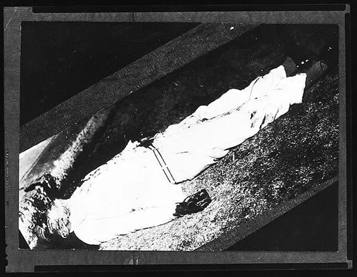 [Copy of Newspaper File Photograph: Corpse with Blood-Spattered Head on Grass, Probably Havana]