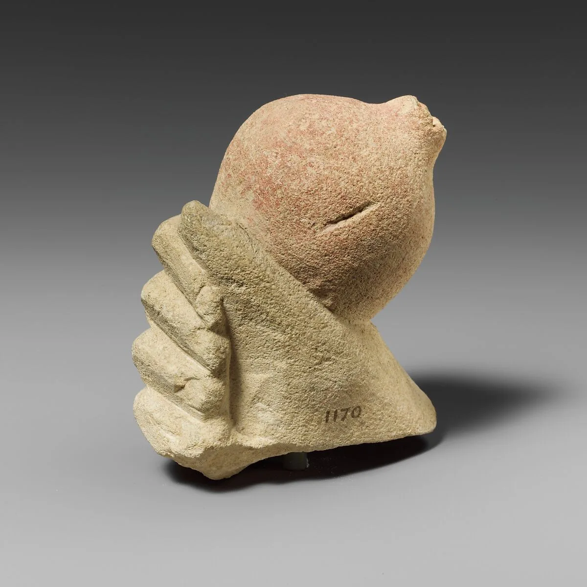 Limestone hand holding a pomegranate — Unknown