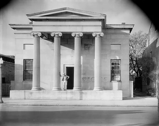 [Greek Revival Building with "SIGNS" Painted on Façade and Man Leaning on Column, Natchez, Mississippi]
